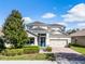 Charming two-story home featuring a brick driveway, blue accents, and manicured landscaping at 15863 Citrus Grove Loop, Winter Garden, FL 34787