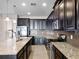 Modern kitchen featuring dark cabinets, stainless steel appliances, granite countertops, and a spacious island with a sink at 15863 Citrus Grove Loop, Winter Garden, FL 34787