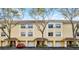 Charming yellow two-story townhome with a tile roof, white trim, garages, and manicured landscaping at 1616 Legacy Park Dr # 1616, Maitland, FL 32751