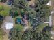 Aerial view of house with screened pool, sand volleyball court, circular drive, and wooded lot at 19709 W Eldorado Dr, Eustis, FL 32736