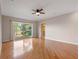 Bedroom with hardwood floors, ceiling fan, and a large window with view to the outdoors at 19709 W Eldorado Dr, Eustis, FL 32736