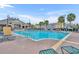 Sparkling community swimming pool surrounded by lounge chairs and lush palm trees on brick patio at 2602 Lodi Cir # 105, Kissimmee, FL 34746