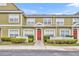 Inviting townhome showcasing a red front door, complemented by manicured bushes and classic white trim at 2602 Lodi Cir # 105, Kissimmee, FL 34746