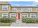 Charming townhouse featuring a bright red door and meticulously manicured front yard with lush green shrubbery at 2611 Gala N Rd # 105, Kissimmee, FL 34746