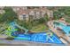 Aerial shot of community pool with waterslides, and seating, next to apartments, with green landscaping at 2621 Archfeld Blvd, Kissimmee, FL 34747