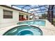 A screened in pool with hot tub, patio lounge area and sunny ambiance for outdoor enjoyment at 2621 Archfeld Blvd, Kissimmee, FL 34747