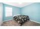 Bright bedroom with blue walls, carpet floors and a floral-patterned bed with natural light from the window at 4418 Blackbird St, Kissimmee, FL 34746
