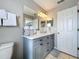 Bathroom with gray vanity, white countertop, double sinks and black hardware at 569 La Mirage St, Davenport, FL 33897