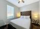 Cozy bedroom with tufted headboard, complemented by hardwood floors, natural light, and matching bedside lamps at 569 La Mirage St, Davenport, FL 33897