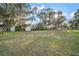 Expansive backyard featuring lush green grass and mature trees and storage buildings at 5790 Se 119Th Pl, Belleview, FL 34420