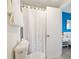 Clean bathroom with a toilet, shower with curtain, and an open doorway to the adjacent blue bedroom at 6165 Carrier Dr # 2306, Orlando, FL 32819