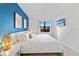 Stylish main bedroom with a king bed, blue accent wall, modern decor, and a view of palm trees from the window at 6165 Carrier Dr # 2306, Orlando, FL 32819