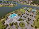 An aerial view of a community clubhouse, pool, tennis courts, and surrounding homes along a waterfront at 8456 Norwich Way, Mount Dora, FL 32757