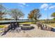 Outdoor stone fire pit with chairs overlooking a lake in a landscaped common area at 8456 Norwich Way, Mount Dora, FL 32757