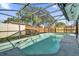 Backyard pool with screened enclosure and a view of the wood fence and green trees at 1017 Bluejack Oak Dr, Oviedo, FL 32765