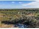 Expansive aerial view of a wooded lot with dense trees, foliage and grass under a blue sky filled with cumulus clouds at 1218 Normandy Dr, Haines City, FL 33844