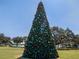 A huge decorated outdoor Christmas tree with colorful ornaments under a clear blue sky at 1218 Normandy Dr, Haines City, FL 33844