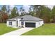 Well-maintained single-story home featuring a modern design with white exterior and a gray two car garage at 16074 Sw 49Th Court Rd, Ocala, FL 34473