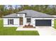 Charming single-story home with modern white exterior, gray roof and a dark gray two car garage at 16074 Sw 49Th Court Rd, Ocala, FL 34473