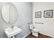 Well-lit powder room with a floating sink, round mirror, and blue accent wall at 2563 Kinsale Ln, Ormond Beach, FL 32174