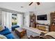 Cozy living room features a large window, wood floors, a plush blue sofa, and a vintage-style wooden coffee table at 2606 Pinyonpine Ln, Sanford, FL 32773