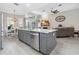 Kitchen island with gray cabinets, stainless steel dishwasher, and view to the living room at 2929 University Acres Dr, Orlando, FL 32817