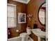 Stylish powder room with a decorative mirror, modern fixtures, and warm, inviting paint at 3668 Peppervine Dr, Orlando, FL 32828