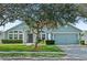 Charming single-story home with a lush green lawn, mature tree, and light blue exterior at 38 Lakeview Reserve Blvd, Winter Garden, FL 34787