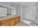 Well-lit bathroom featuring a bathtub and shower with white tiles, a light wood vanity with a mirror and a door at 4012 Santa Maria Dr # 102, Kissimmee, FL 34741