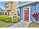 Townhome entrance featuring a vibrant red door, colorful siding, and manicured landscaping at 4012 Santa Maria Dr # 102, Kissimmee, FL 34741