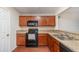 Galley kitchen featuring wood cabinets, black appliances, and faux granite countertops at 610 Carolina Ave, St Cloud, FL 34769