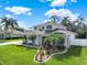 Beautiful two-story home with lush landscaping, palm trees, and manicured lawn on a sunny day with scattered clouds at 795 Sterling Chase Dr, Port Orange, FL 32128