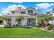 Beautiful two-story home with well-manicured lawn, lush landscaping, palm trees, and charming blue double-door entrance at 795 Sterling Chase Dr, Port Orange, FL 32128