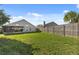 Spacious backyard features green grass, wood fence, and the home's exterior with a screened-in porch at 8523 Fort Clinch Ave, Orlando, FL 32822