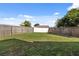 Large backyard with a wood fence, green grass, and blue skies with fluffy white clouds at 8523 Fort Clinch Ave, Orlando, FL 32822