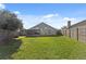 Green backyard features lush grass, a wood fence, and the home's exterior with a screened-in porch at 8523 Fort Clinch Ave, Orlando, FL 32822