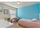 Bright bedroom with blue accent wall, featuring a twin bed, desk, tv and great natural light at 9559 Silver Buttonwood St, Orlando, FL 32832