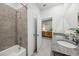 Bright bathroom featuring a granite double sink vanity, a shower with beige tiling, and an open doorway at 1206 Normandy Dr, Haines City, FL 33844