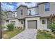 Two-story townhouse with gray color scheme, a garage, and a brick paved driveway at 1213 S Station Pl # 404, Orlando, FL 32809