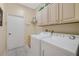 Well-lit laundry room with white cabinets and appliances, sink, and tile flooring at 126 Seville Chase Dr, Winter Springs, FL 32708