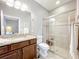 Bathroom with glass-door shower, dark wood vanity, granite countertop, large mirror, and tile flooring at 1374 Zeek Ridge St, Clermont, FL 34715