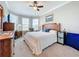 Bedroom with a ceiling fan, bay window, carpeted floor, white bedding, wooden furniture, and light gray walls at 1374 Zeek Ridge St, Clermont, FL 34715