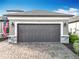 A gray, two car garage, with paver driveway and stone accents at 1374 Zeek Ridge St, Clermont, FL 34715