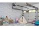 Garage space converted to playroom, showcasing faux brick wall, geometric flooring and overhead garage door at 181 N Phelps Ave, Winter Park, FL 32789