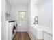 Bright laundry room with white farmhouse sink, modern washer and dryer and subway tiles at 181 N Phelps Ave, Winter Park, FL 32789