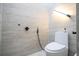 Neutral colored tiled half-bathroom featuring a modern toilet, shower-head attachment, and sleek lighting fixture at 181 N Phelps Ave, Winter Park, FL 32789