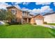 Inviting two-story home with a lush green lawn, complemented by mature landscaping and a welcoming front porch at 1920 Partin Terrace Rd, Kissimmee, FL 34744