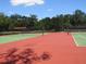 Well-maintained red and green tennis courts surrounded by mature trees, providing a space for recreational sports at 1920 Partin Terrace Rd, Kissimmee, FL 34744