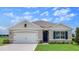 Charming single-story home featuring a two-car garage, blue shutters, manicured lawn, and a welcoming front entrance at 2117 Pigeon Plum Dr, Haines City, FL 33844