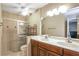 Bathroom featuring double sinks, wood cabinets, a large mirror, and a shower with glass doors at 2811 Curry Woods Dr, Orlando, FL 32822